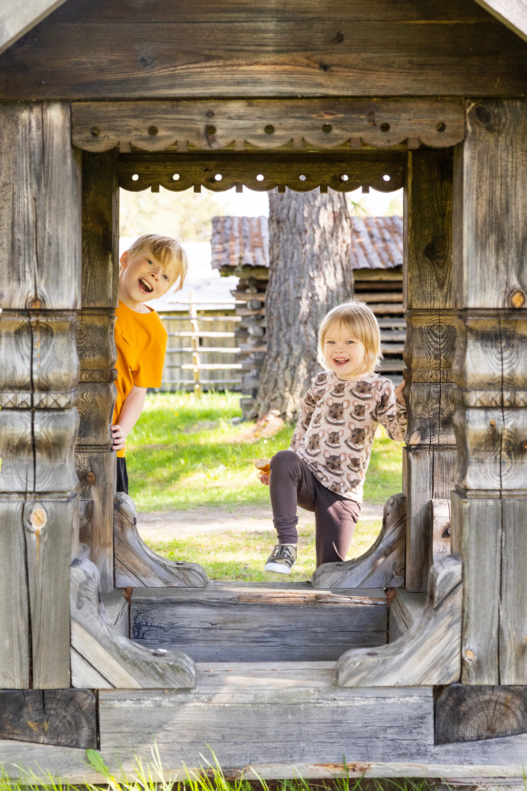 Lapset kurkistelevat Pielisen museon rakennusten välistä
